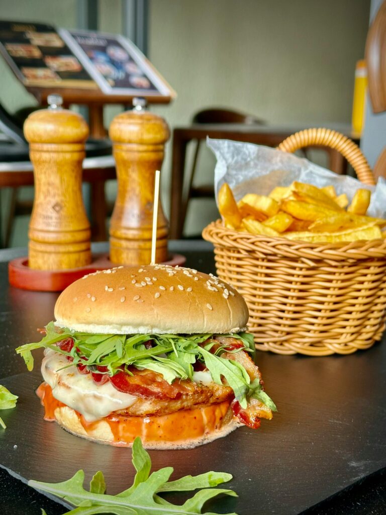 Mouthwatering cheeseburger topped with arugula and a side of crispy fries in Ho Chi Minh cafe.